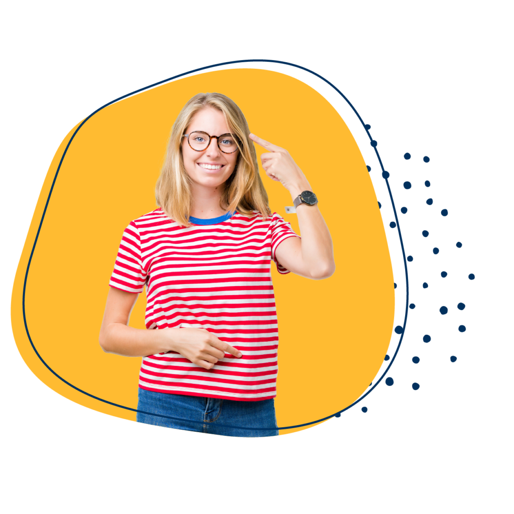 Junge Frau in rot geringelten T-Shirt vor einem gelben Hintergrund zeigt auf ihren Kopf und lächelt freundlich in die Kamera.