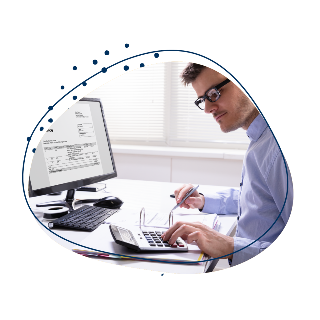 Mann im lila Hemd arbeitet an einem Schreibtisch mit zwei Monitoren, Taschenrechner und Ordner, analysiert Daten.