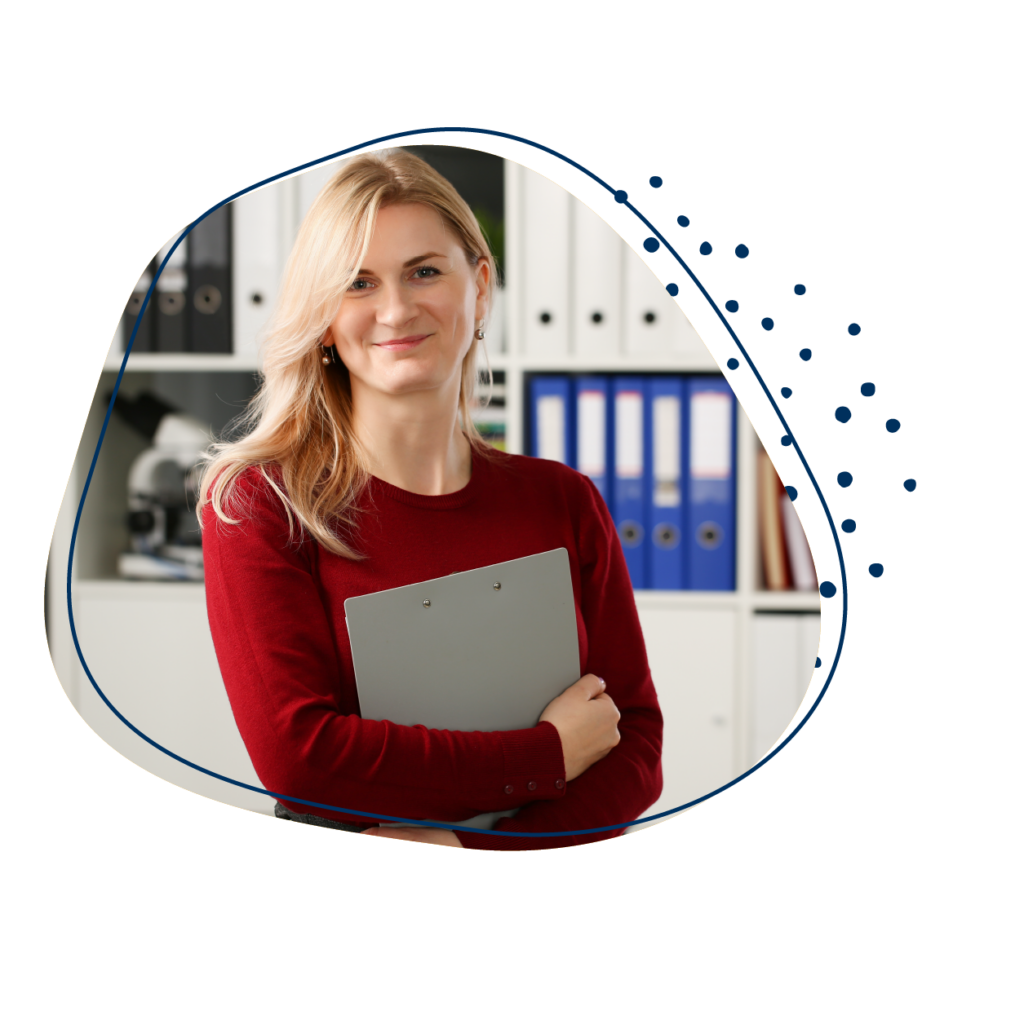 Junge Frau mit leuchtend roten Pullover steht mit einer Klemmmappe vor einem Aktenordnerregal und lächelt in die Kamera.