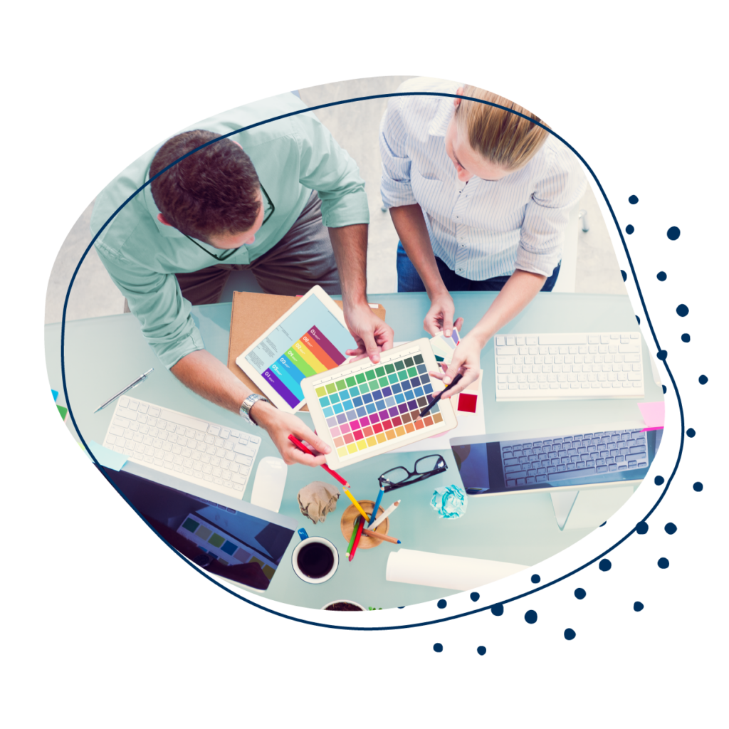 Mediengestalter bei der Farbauswahl, Draufsicht auf Schreibtisch mit Farbmustern und Bildschirm.